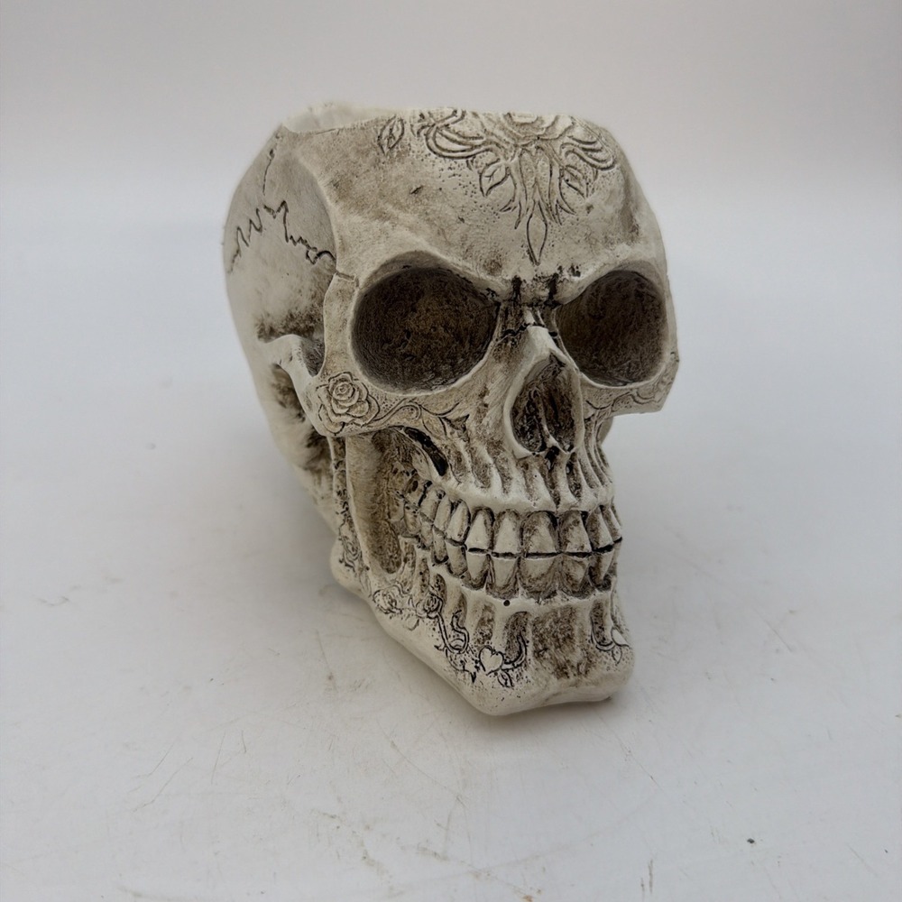 white resin skull planter features intricate carved floral filigree details